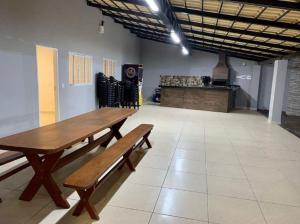 Senador CanedoにあるEspaço Venezaの木製テーブルとベンチ付きの広い客室です。