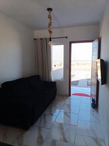 a living room with a black couch on a tile floor at Relaxe à Beira-Mar com pé na areia! in Tramandaí