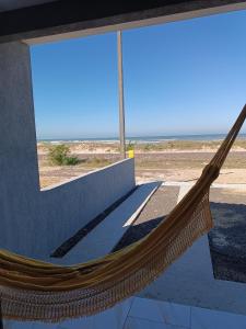 a hammock in a building with a view of the ocean at Relaxe à Beira-Mar com pé na areia! in Tramandaí