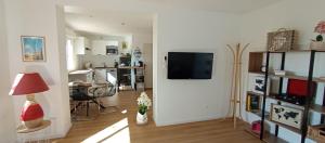 a living room with a television and a living room with a table at Maison duplex Bisca avec jardin in Biscarrosse