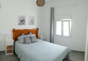 a white bedroom with a bed and a window at Ático Sol & Mar - La Línea in La Línea de la Concepción
