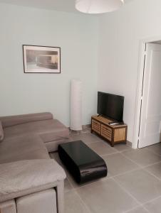 a living room with a couch and a tv at Ático Sol & Mar - La Línea in La Línea de la Concepción