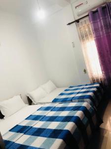 a blue and white bed in a room with a window at PEONY luxury Homestay - Anuradhapura in Anuradhapura +14 photos