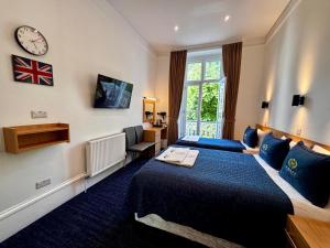 Habitación de hotel con cama y reloj en la pared en Jubilee Hotel Victoria, en Londres