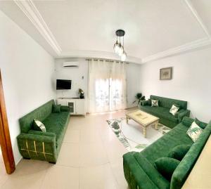 a living room with green couches and a table at Mina résidence A1 in Kelibia