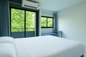 a white bed in a room with two windows at Siam Rama9 Hotel in Bangkok