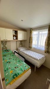 a room with two beds and a window at Privately Owned 2-bedroom Caravan at Camber Sands, 1 sofa bed, Private Parking, NO SMOKING NO PETS in Camber