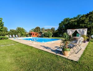 a swimming pool with two chairs and a house at La Borie du Chevrier in Sainte-Croix-de-Beaumont