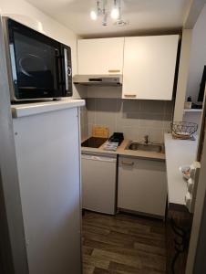 a small kitchen with a microwave and a sink at T2 centre ville, 150m du lac, parking - Thermes in Évian-les-Bains