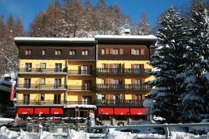 un gran edificio de apartamentos con nieve en el suelo en Hotel Etoile De Neige, en Valtournenche