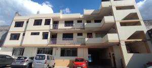 a white building with cars parked in front of it at Hotel LaJoya in Otavalo