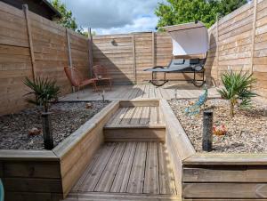 a garden with a chair and a bench on a wooden deck at HORIZON SPA in Samer