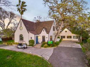 a white house with a car parked in the driveway at Tudors Village BNB in Fair Oaks