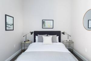 a white bedroom with a large bed with two lamps at 200mbps speeds Laundry Long Stays in Boston
