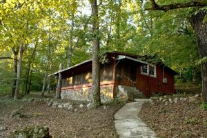 a log cabin in the woods with a path in front at The Manor at Becks Lake in Rockmart