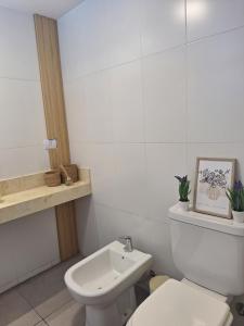 a white bathroom with a toilet and a sink at Departamento Premium Tucuman in San Miguel de Tucumán