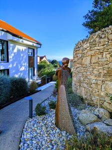 a statue of a woman in a dress next to a stone wall at Hotel Spa Meiga do Mar in Carnota