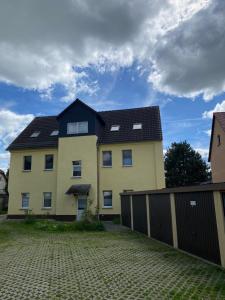 a large yellow house with a black roof at Cozy studio apartment in Hohenmölsen