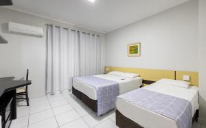 a hotel room with two beds and a desk at Bristol Exceler Campo Grande in Campo Grande