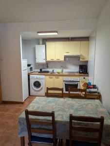 a kitchen with a table and chairs and a kitchen with a washing machine at Casa espelunciecha in Biescas