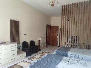 a bedroom with a bed and a dresser and chairs at Ami guest house in Fier