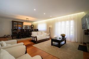 a living room with white furniture and a dining room at Casa Alto da Ribeira - Alojamento local in Póvoa de Lanhoso