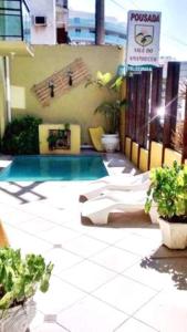 a pool with chaise lounges and a sign on a building at Pousada Vale do Amanhecer in Cabo Frio