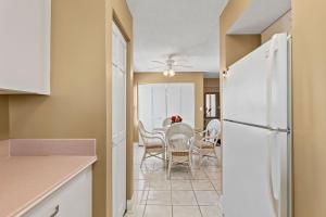 une cuisine avec une table et un réfrigérateur blanc dans l'établissement Direct oceanfront corner condo with spacious balcony and heated beachfront pool, à Ormond Beach 32 autres photos