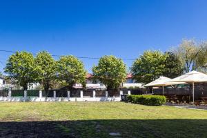 a park with tables and umbrellas and trees at Vila Cornelius in Costinesti