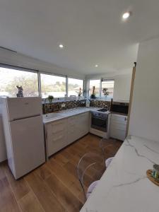 eine große Küche mit weißen Geräten und Fenstern in der Unterkunft Charmant Studio in La Motte-dʼAigues