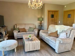 a living room with two couches and a chandelier at Au Coeur des Collines, Doucette in Ellezelles