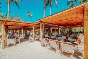 a restaurant with tables and chairs and palm trees at Grand Palladium Imbassaí Resort & Spa - All Inclusive in Imbassai