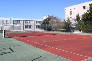 a tennis court in front of a building at Logis Hôtel Le Rochelois in La Rochelle
