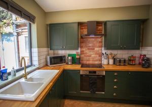 a kitchen with green cabinets and a sink and a stove at NEW Refurbished 2025 Cottage Sleeps 6 Ashbourne Peak District Derbyshire in Ashbourne +29 photos