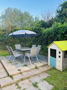 Una mesa y sillas con una sombrilla y una caseta para perros. en Haven Holiday Park, Kent Coast, en Allhallows