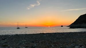 a sunset over the ocean with boats in the water at Les Chambres de Giottani in Barrettali