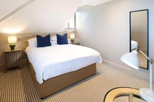 a bedroom with a large white bed with blue pillows at The Kings Arms in Christchurch