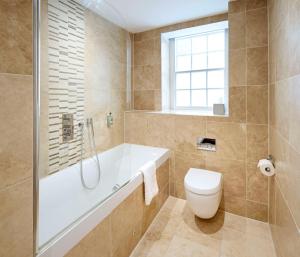 a bathroom with a tub and a toilet and a sink at The Kings Arms in Christchurch