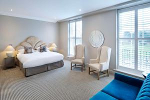 a bedroom with a bed and two chairs and windows at The Kings Arms in Christchurch