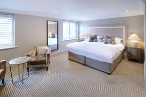a bedroom with a large bed and a chair at The Kings Arms in Christchurch