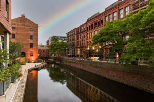 a rainbow over a river in a city with buildings at Velvet Hotel Manchester, WorldHotels Crafted in Manchester