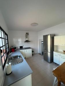una cucina con frigorifero in acciaio inossidabile e mobili bianchi di Whispering Tides Villa a Candelaria Altre 9 foto