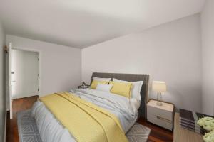 a bedroom with a bed with a yellow blanket on it at SG, Charming Chelsea Balcony Suite in London