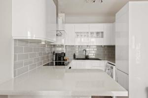 a white kitchen with white cabinets and a sink at SG, Charming Chelsea Balcony Suite in London