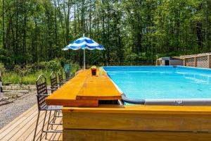 a wooden table with an umbrella next to a swimming pool at PoolHot Tub Firepit Near Hikes Shops Dining Cragswood Lodge by AvantStay in New Paltz