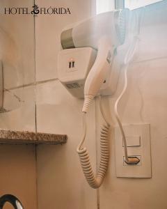a hair dryer hanging on a wall in a bathroom at Hotel Flórida, Triplo - 08 in Poços de Caldas