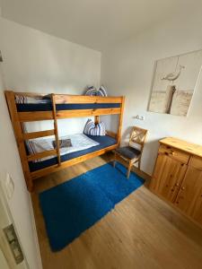 Una habitación con dos literas con una silla y una alfombra azul. en Ferienwohnung Holzteichstraße 11, en Greifswald
