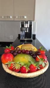 un bol de fruits sur un comptoir avec des fraises et des raisins dans l'établissement Residence Hivernage - Luxe 2 slaapkamer appartement, à Agadir 5 autres photos