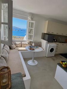 a living room with a table and a kitchen with a window at Blue and white Mykonos in Mikonos