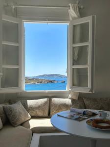a living room with a window with a couch and a table at Blue and white Mykonos in Mikonos